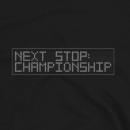 A close up of the Black t-shirt with white text 'Next stop : championship' on a white background