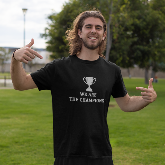 Man wearing a Black short sleeve T-Shirt with 'We Are The Champions' text  with a cup graphic above the wording outdoors